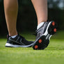The underside of a persons golf shoe showing red and black Pivix golf spikes attached.