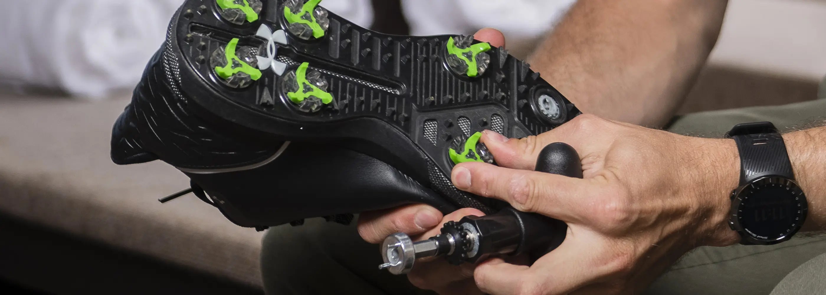 A person using a cleat wrench to change out their tour flex pro golf spikes on their shoe.