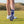 A close-up of a golfer's footwear, showcasing the sole of a white golf shoe with spikes, set on a grassy field.